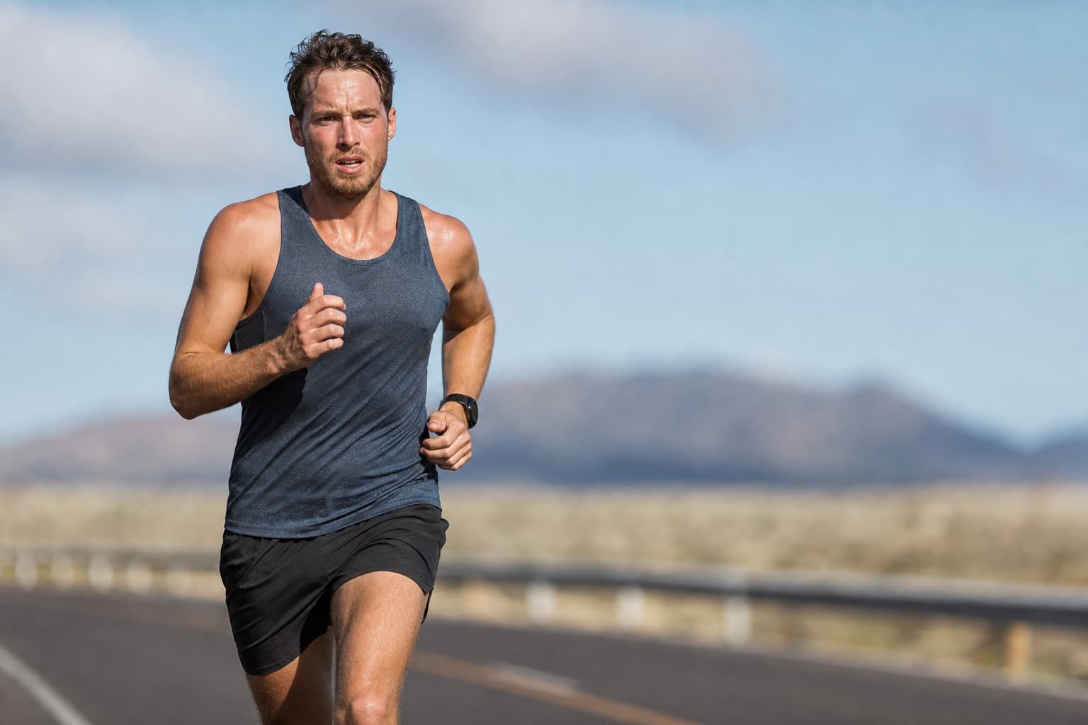 Runner in a focused, committed 10K effort on an open road.