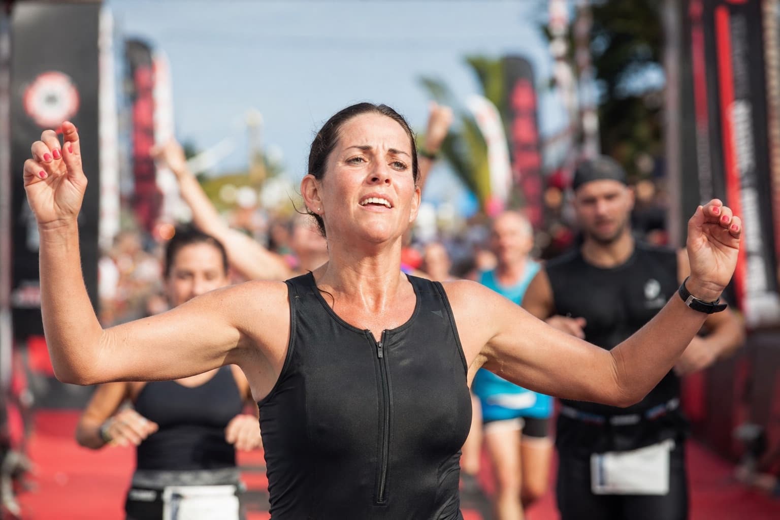 A woman runner finishing a marathon, exhausted but proud in the chute.