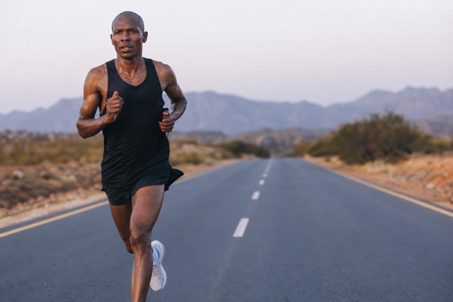 Marathoner pushing a hard, controlled qualifying effort on an open road.