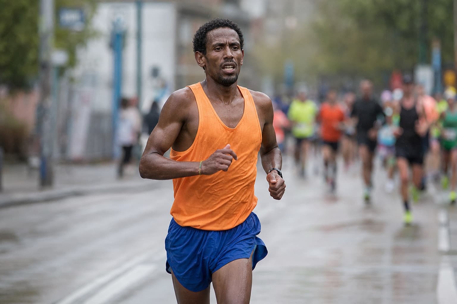 Marathon runner deep in the late miles, fatigued but holding form on a city street.