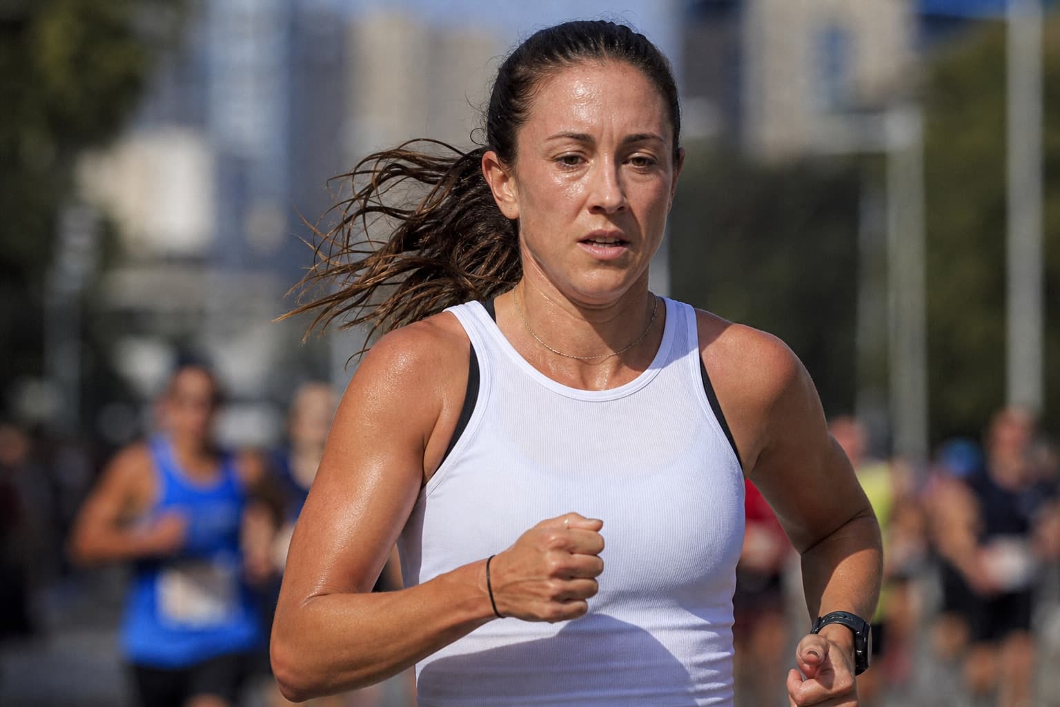 A woman runner in her thirties holding a strong, controlled 10K effort.
