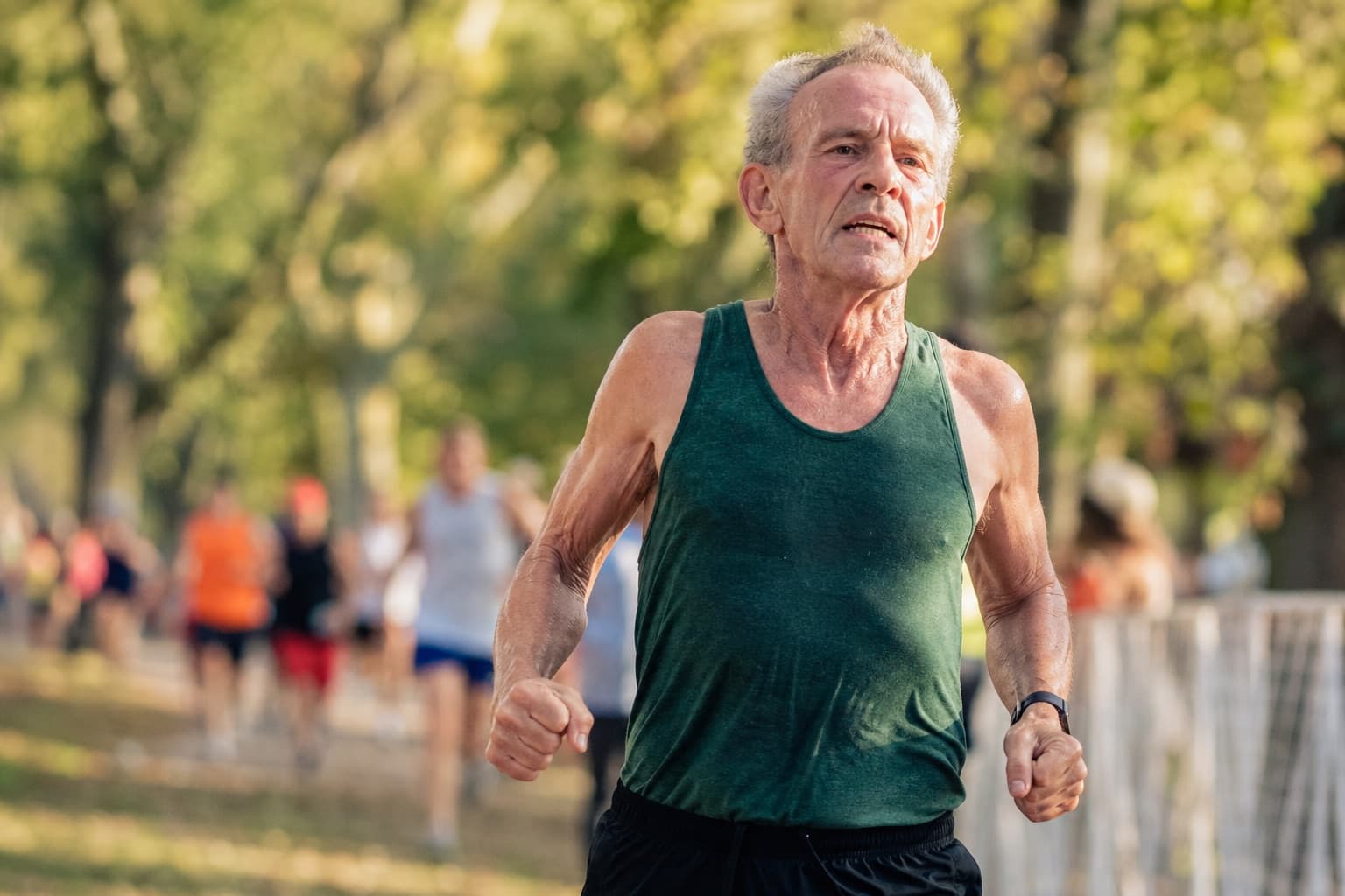 An older runner in his sixties finishing a 5K with a strong stride.