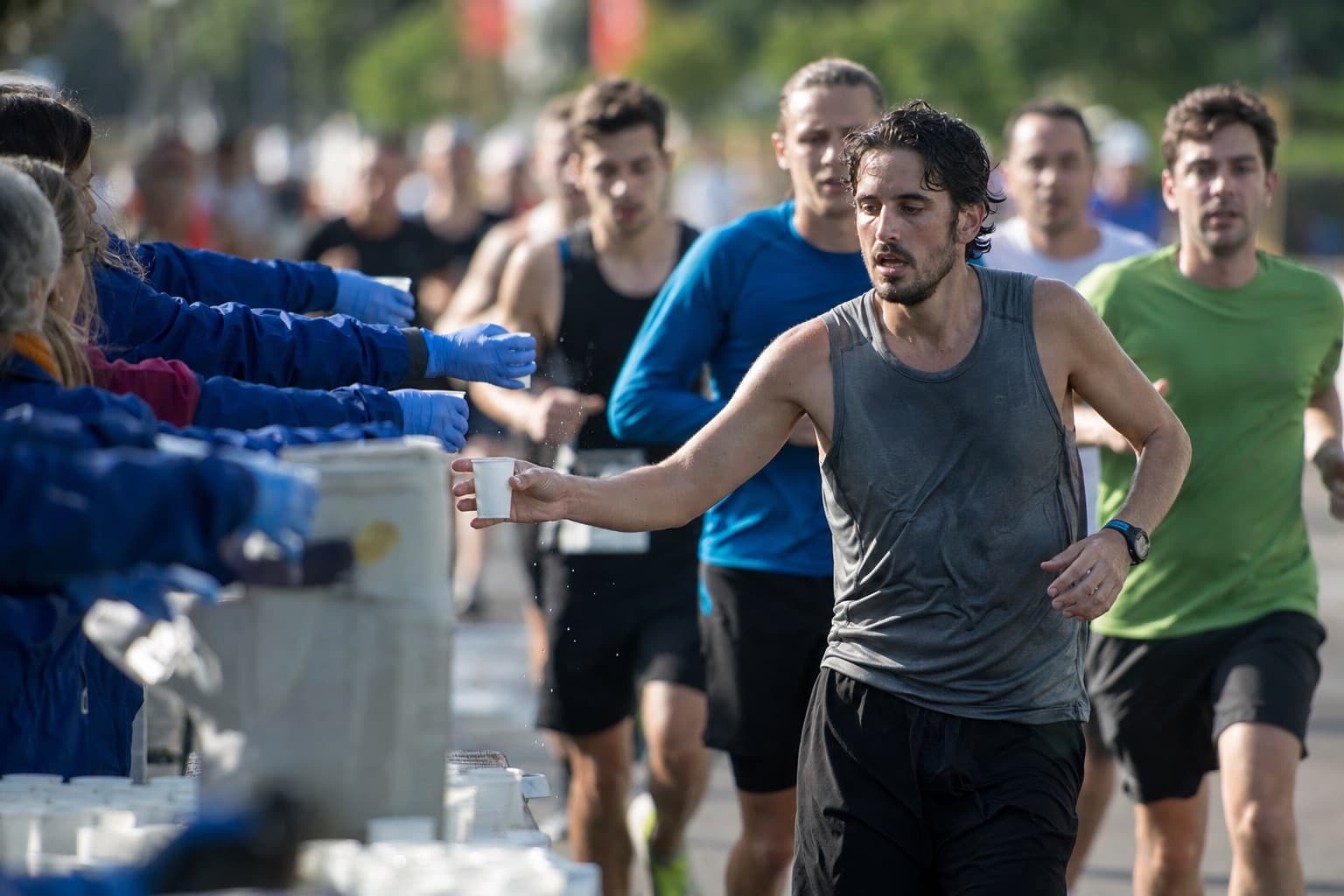 A runner grabbing a cup of water at a marathon aid station.