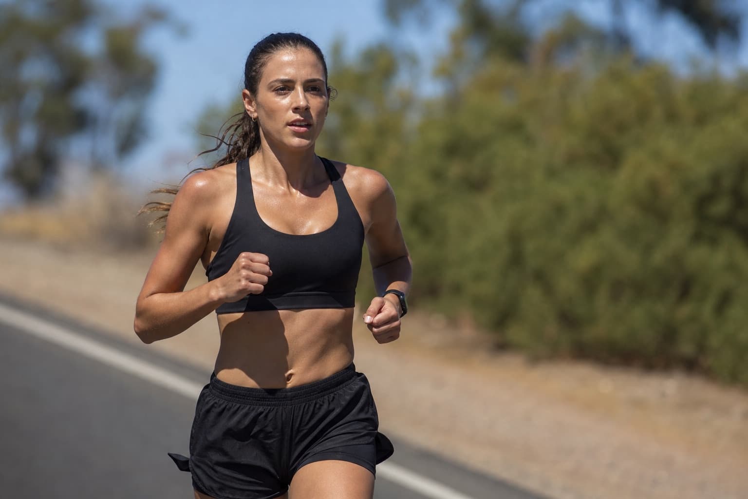 Runner holding a steady, hard tempo effort on an open road.