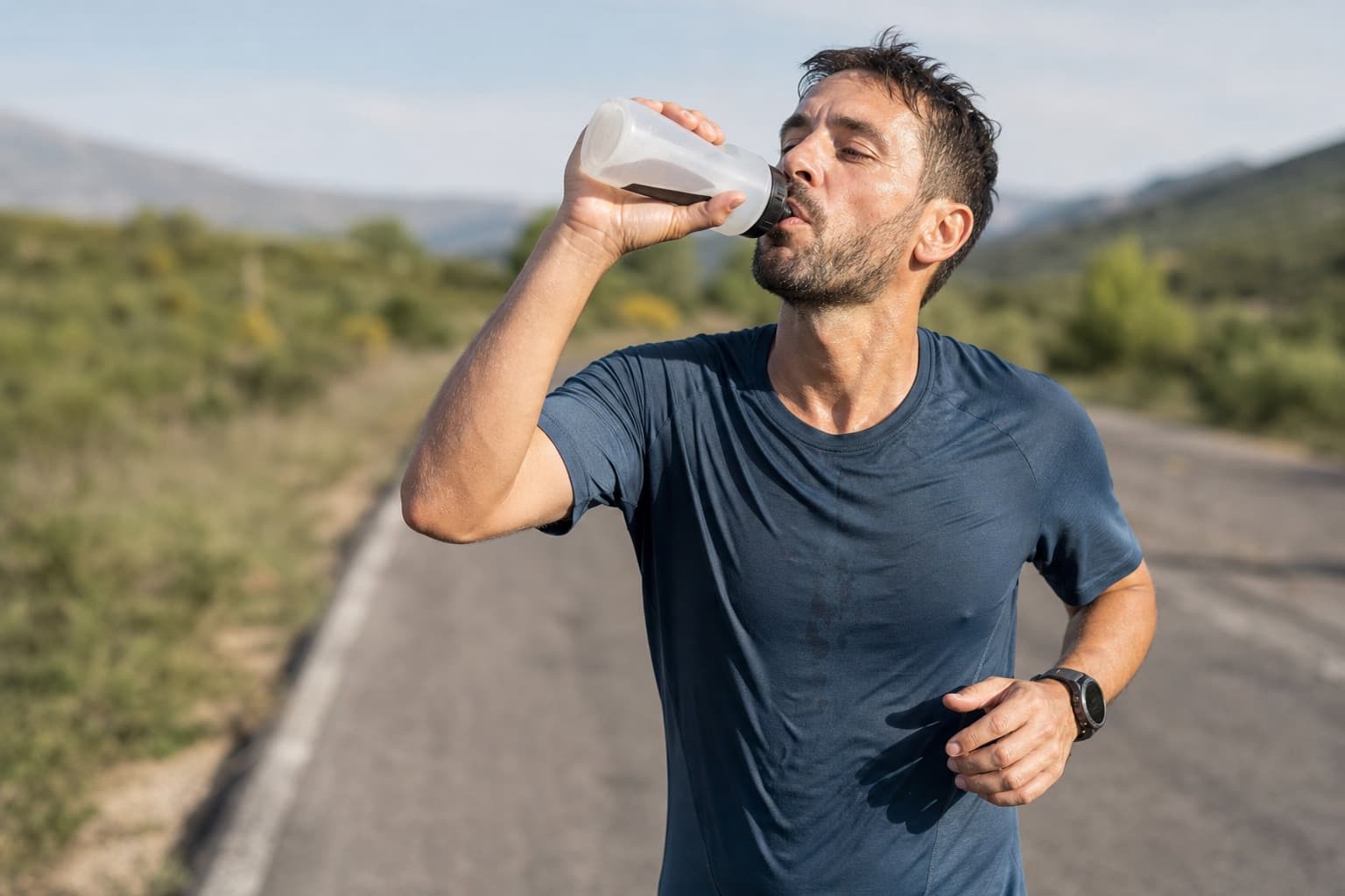 Runner sipping from a handheld bottle during a long training run.