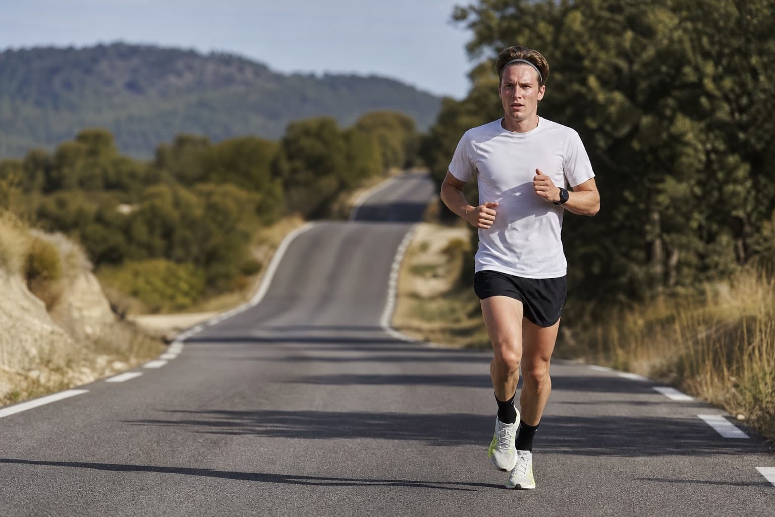 Runner deep into a long endurance training run on a quiet country road.