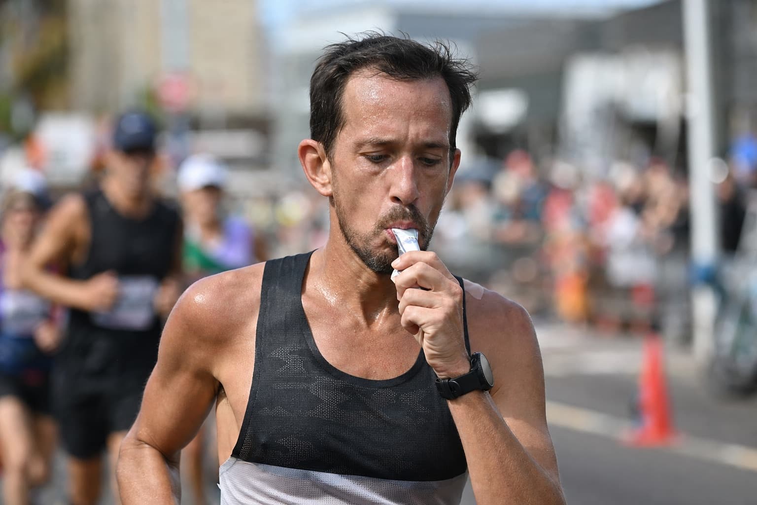Marathon runner squeezing an energy gel into their mouth mid-race.