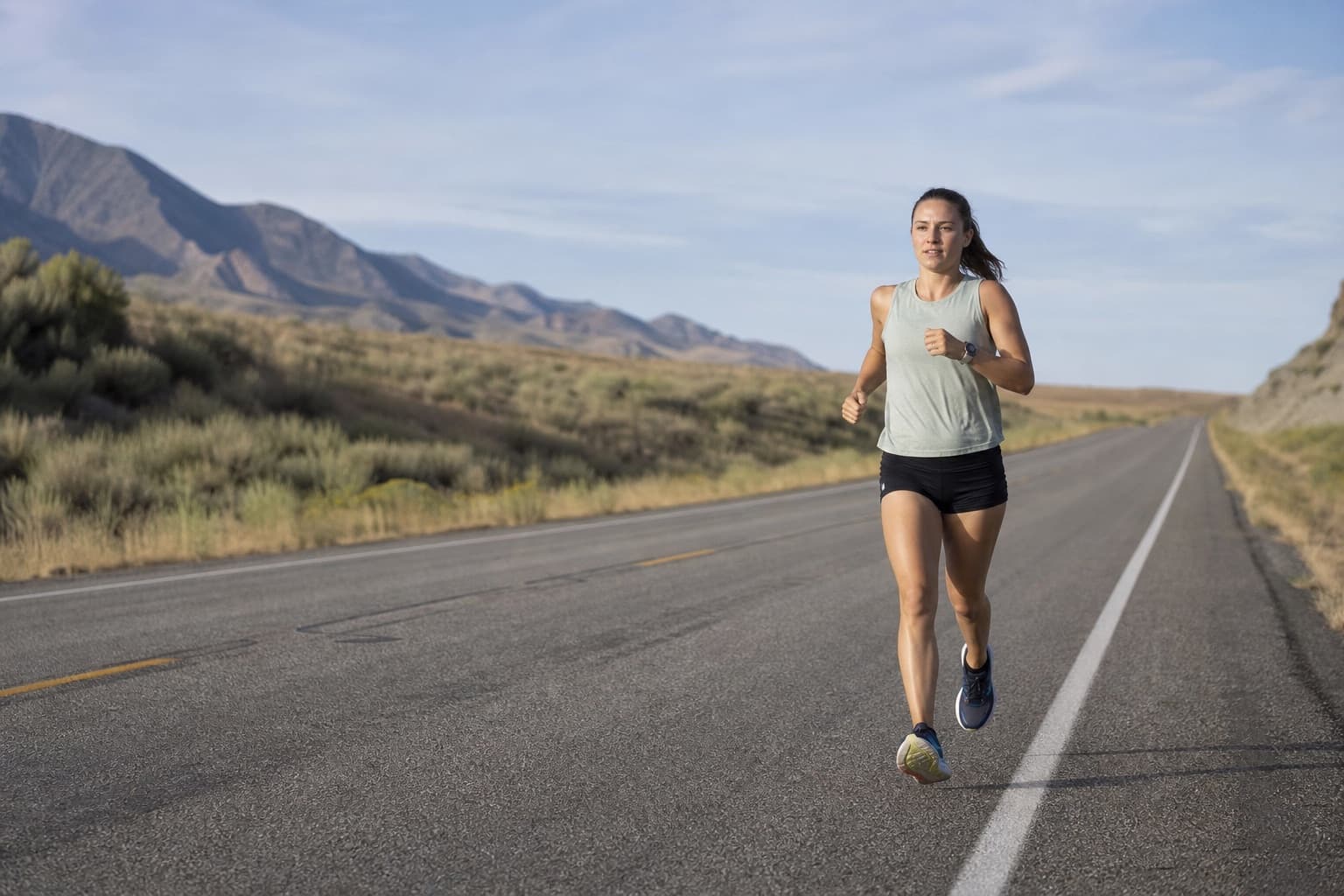 Runner holding a steady, easy pace along a long open road.