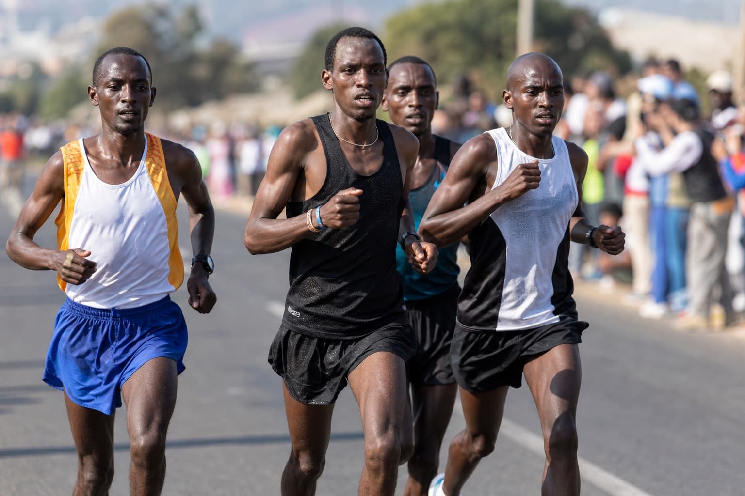 Small pack of marathon runners running together near a pace group past halfway.