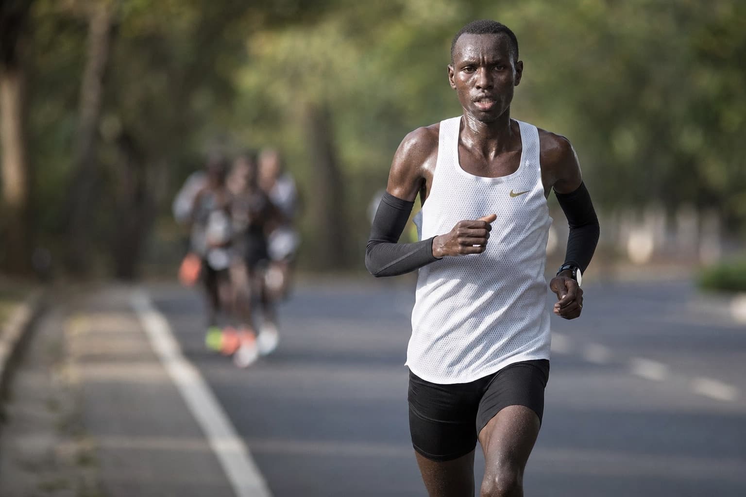Elite-amateur marathoner driving a hard, relentless pace on an open road.