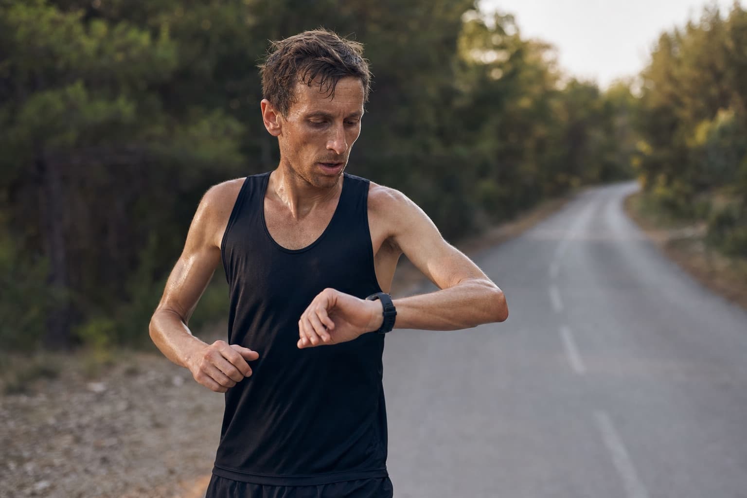 Runner glancing at a wrist watch during a fast-finish long training run.