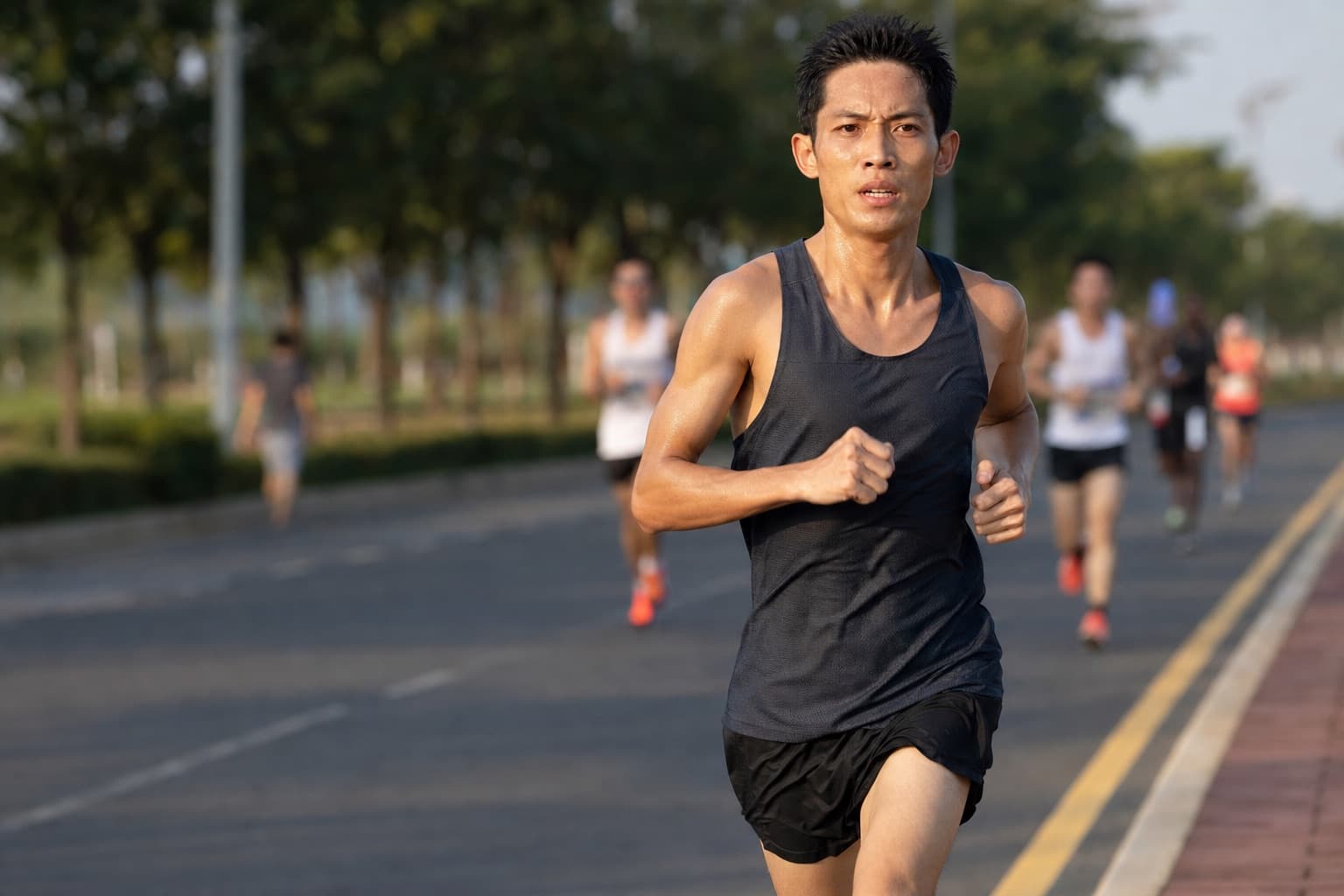 Lean competitive runner holding a fast, controlled threshold pace on the road.