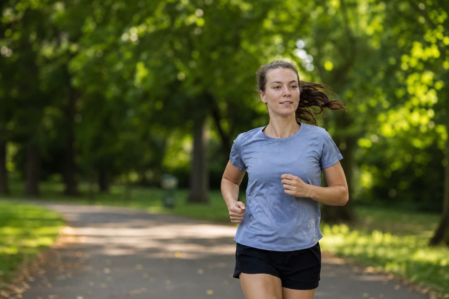 Runner on a relaxed shake-out jog through a green park during marathon taper.
