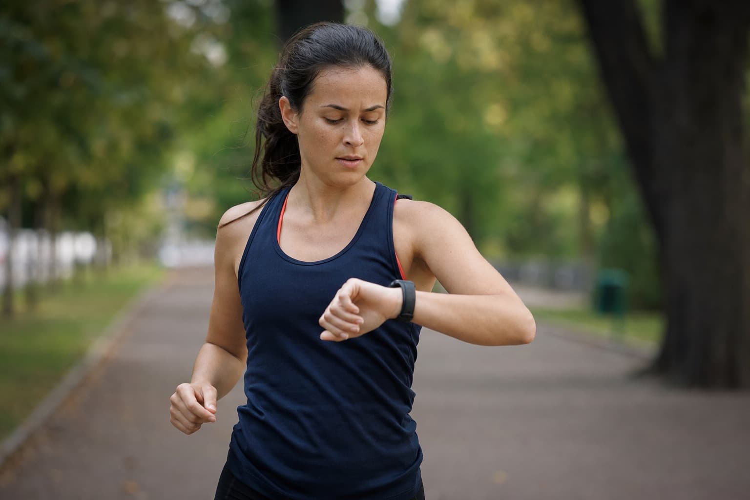 Runner glancing down at a wrist GPS watch mid-run, checking the effort.