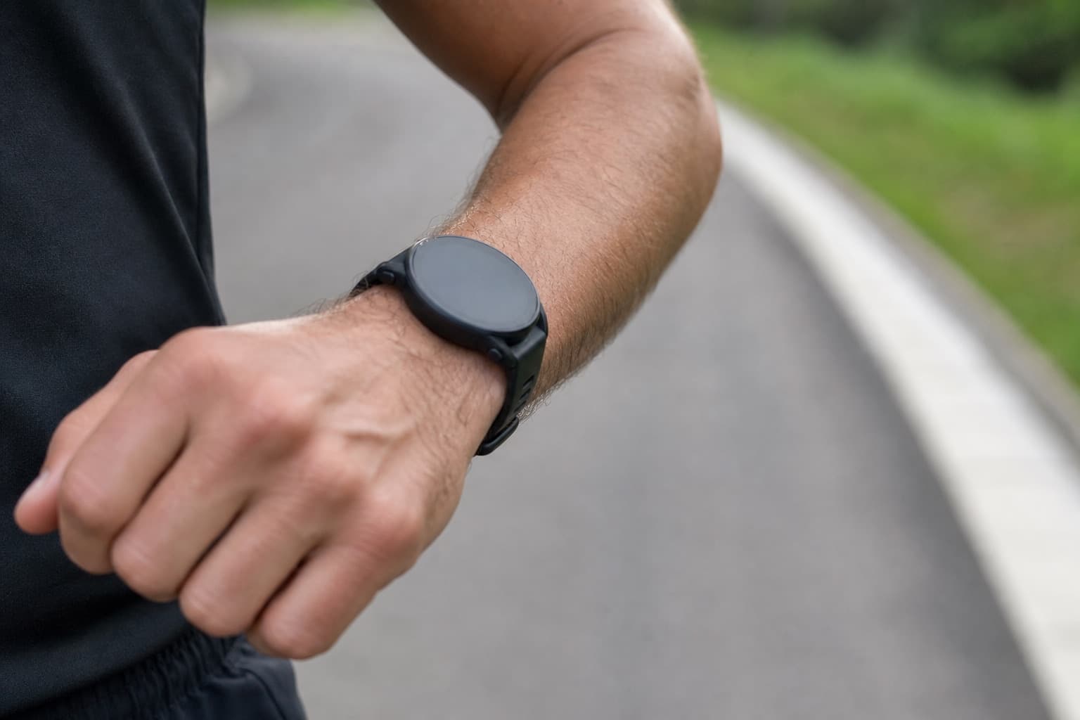 Close-up of a runner's wrist-worn GPS watch during a running stride outdoors.