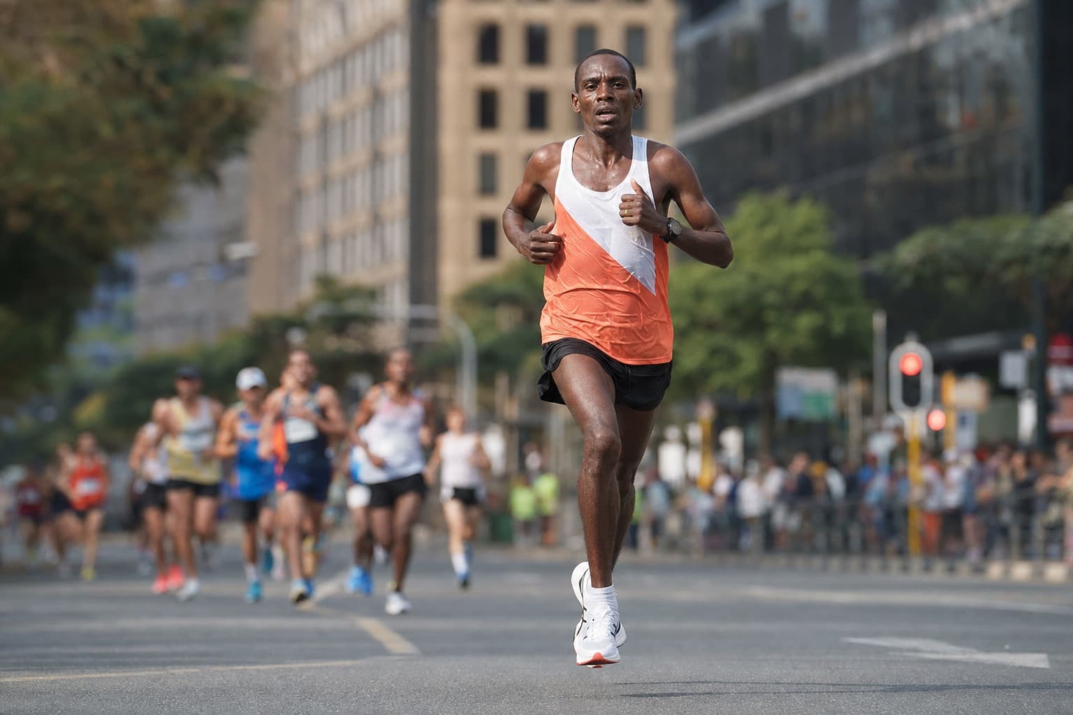 Marathon runner holding a steady, even pace along a city marathon street.