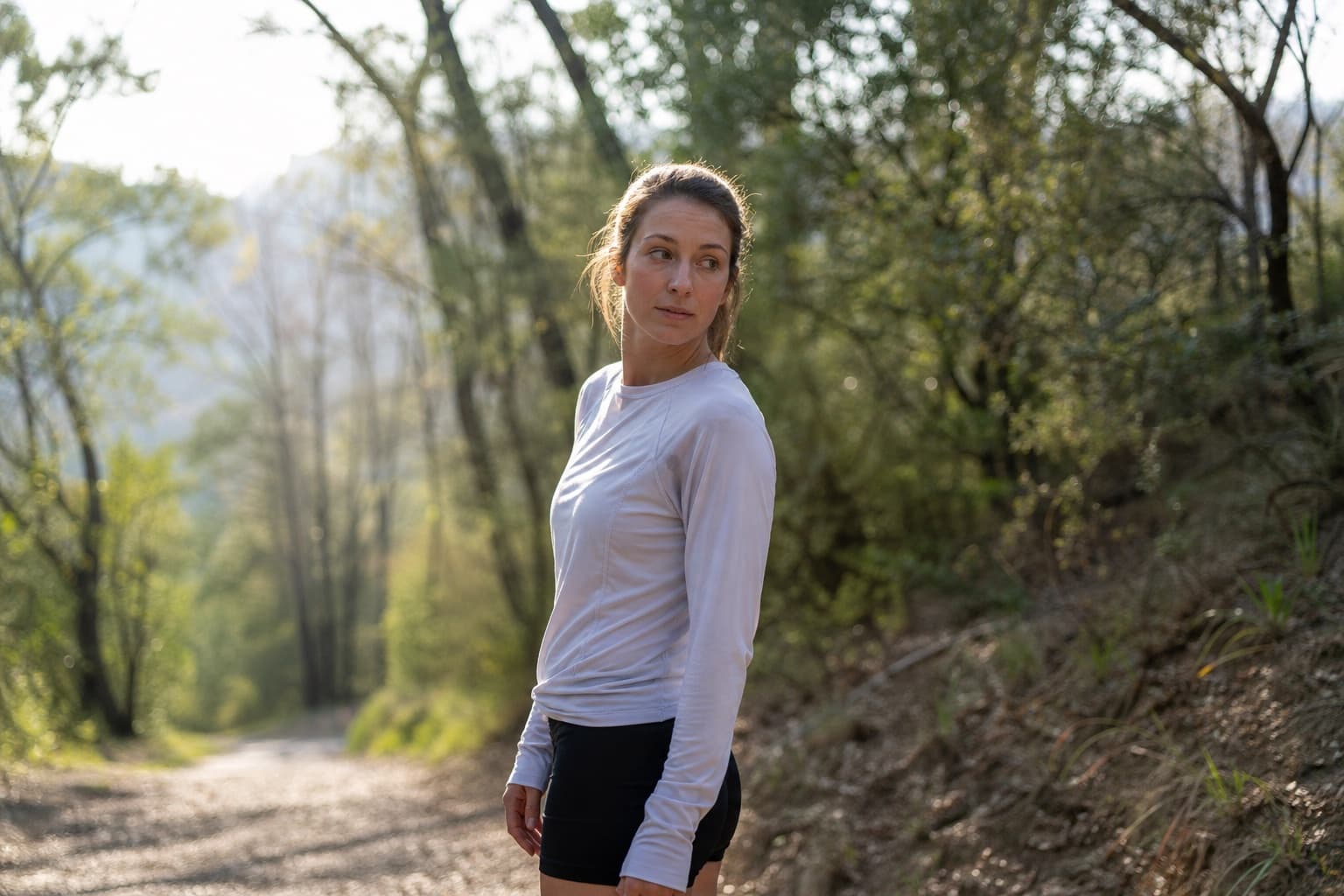 Runner pausing mid-run on a trail, looking back thoughtfully to take stock.