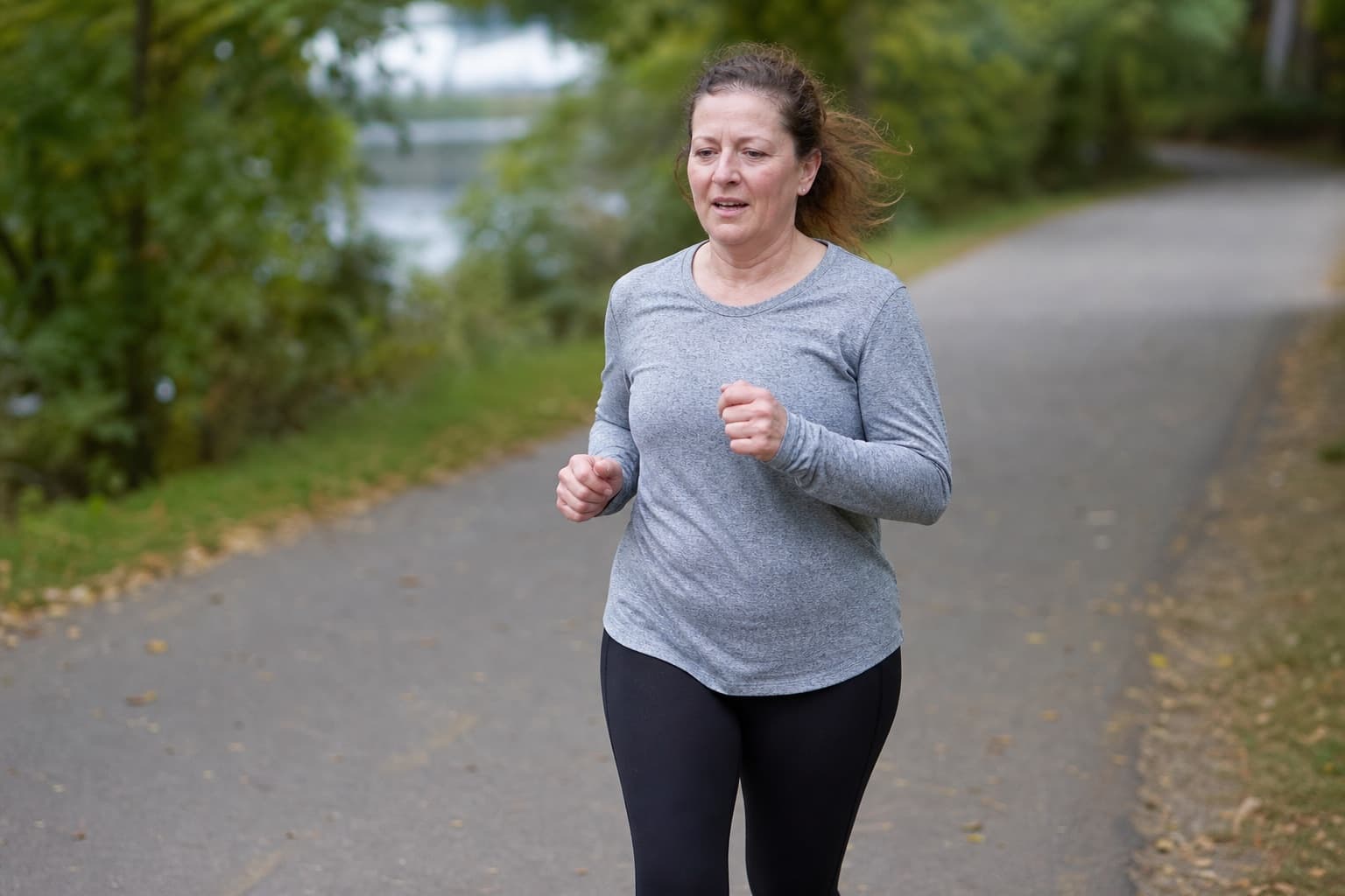 Runner mixing brisk walking with short jogs on a paved park path.
