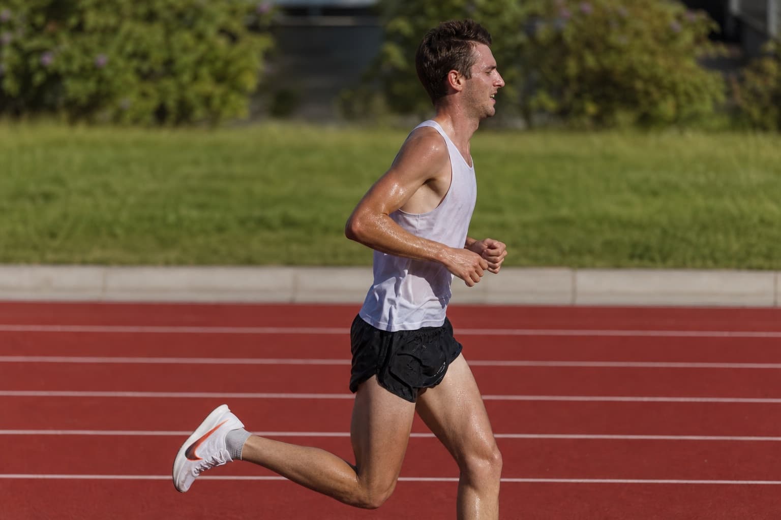 Distance runner holding a hard tempo effort on an outdoor track in daylight.