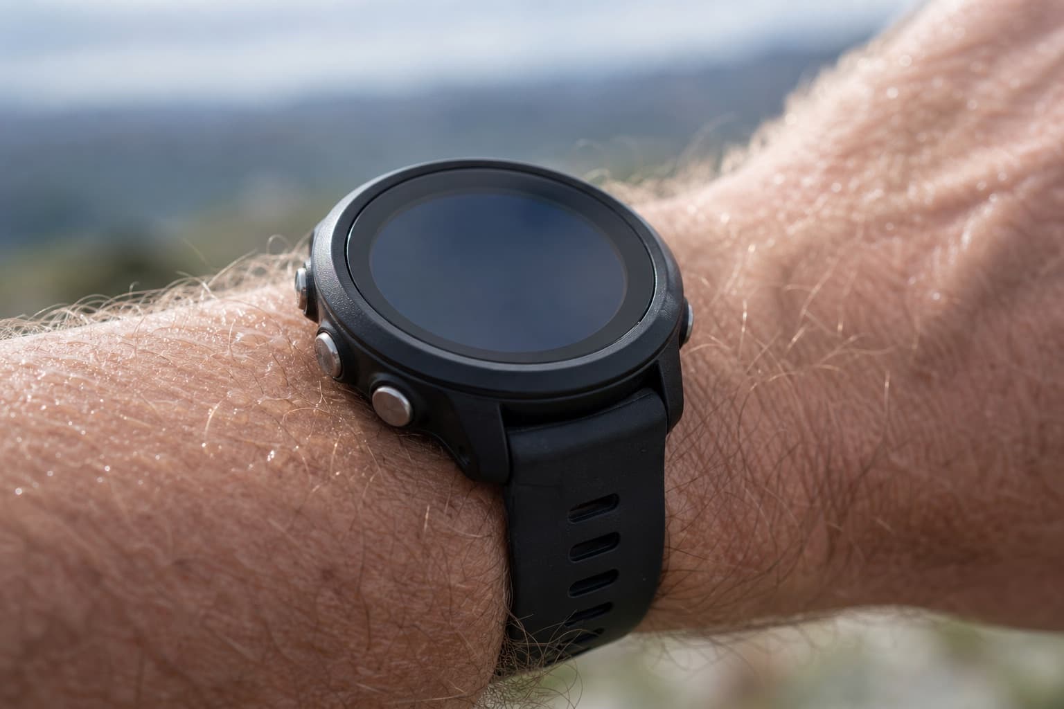 Close-up of a GPS sports watch on a runner's wrist outdoors.