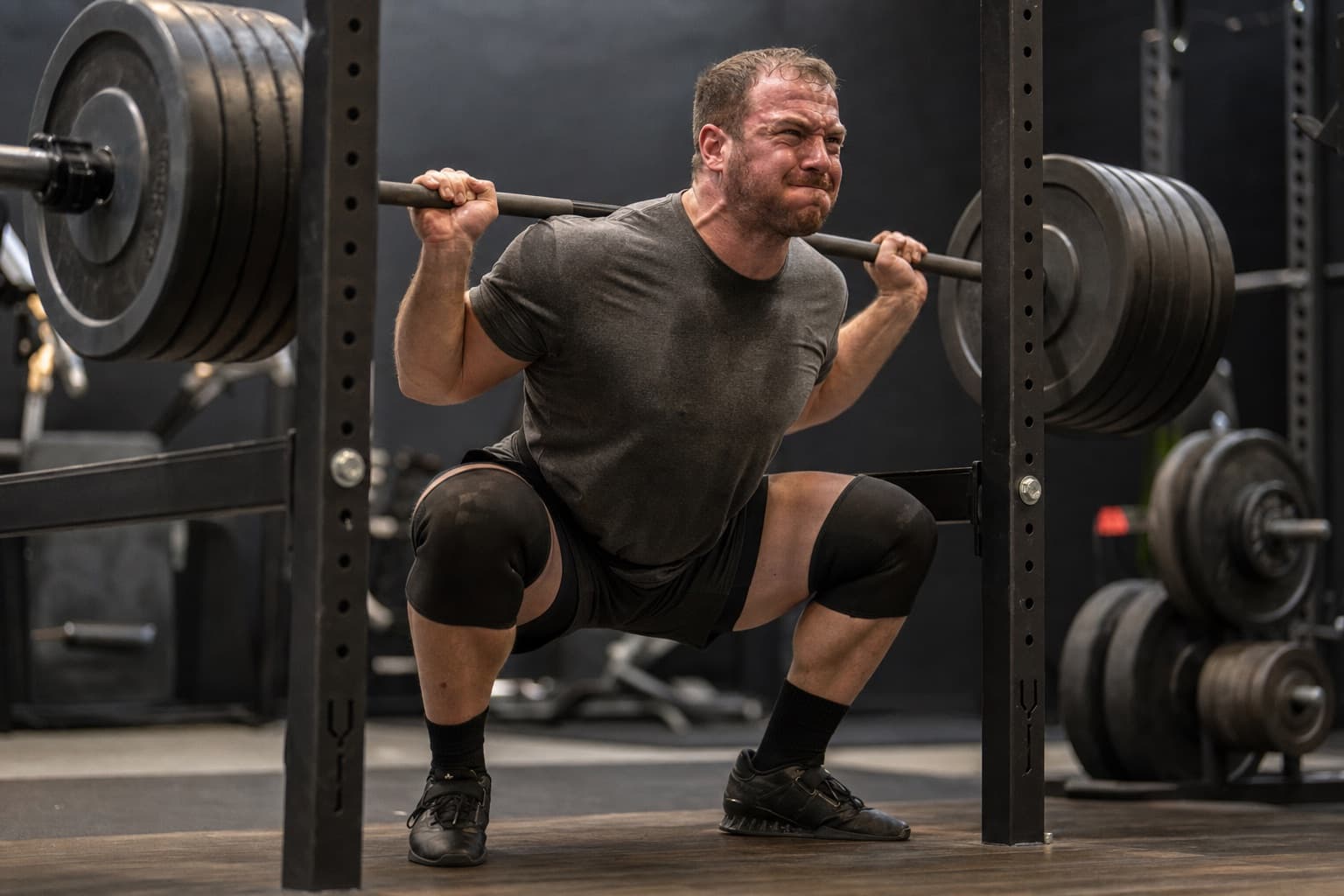 Runner performing a heavy barbell back squat in a gym.