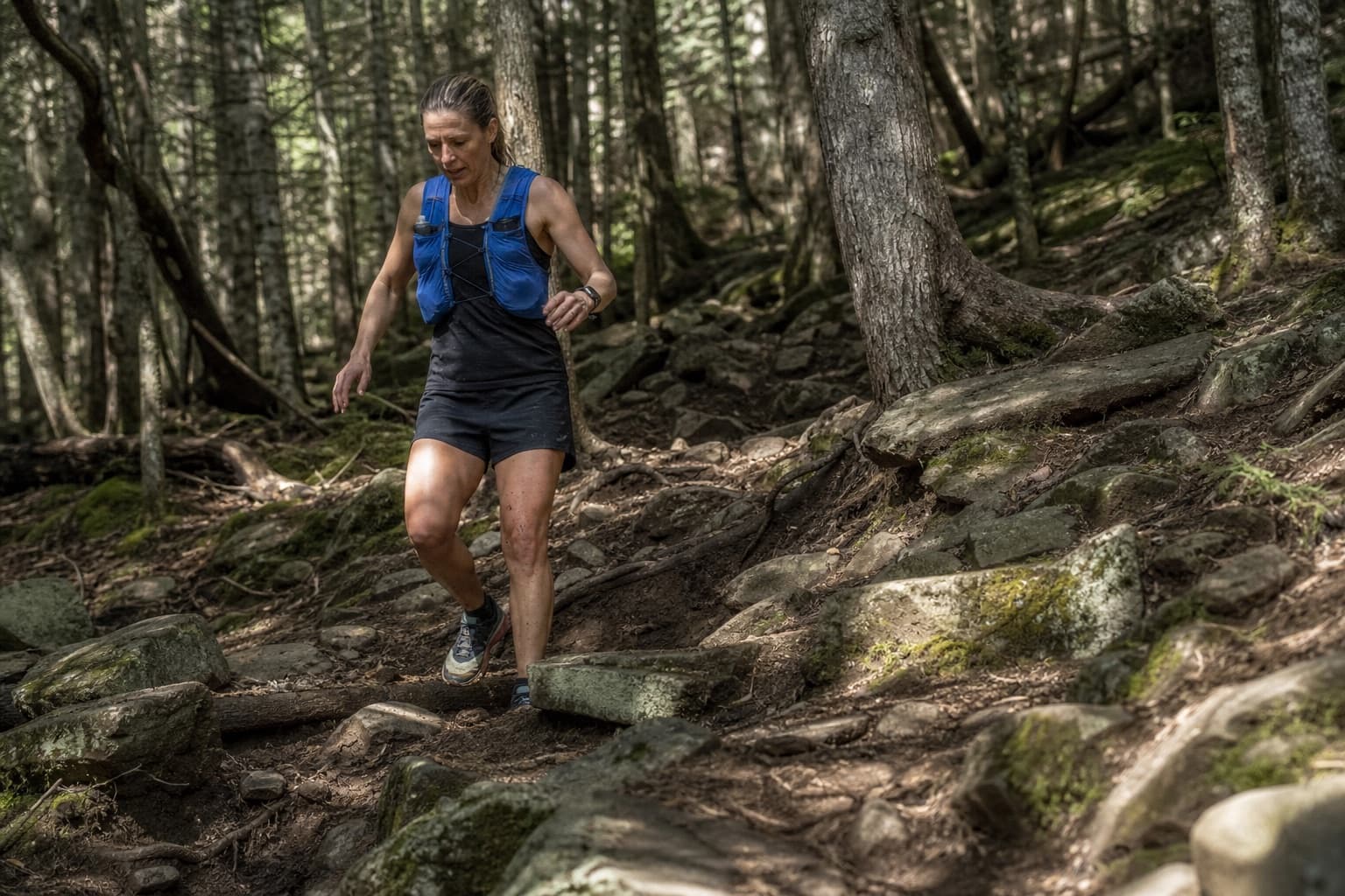 Trail runner navigating a rocky, root-covered forest path.