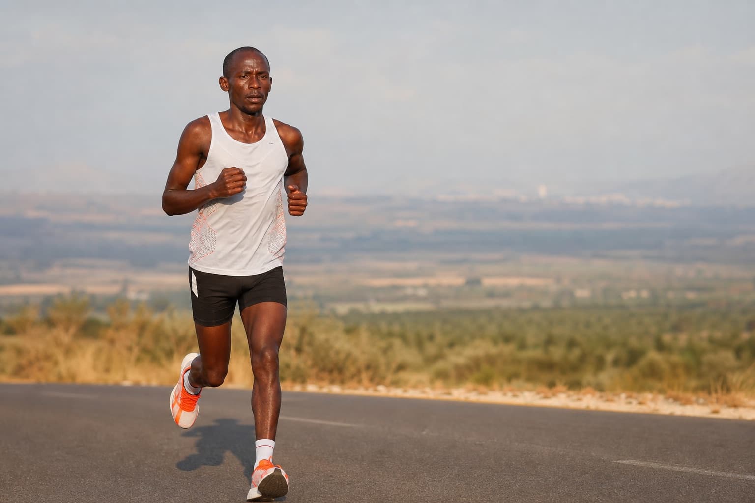 Marathon runner holding an efficient, economical stride on an open road.