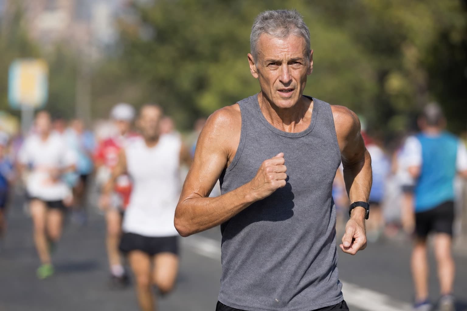 A gray-haired masters runner in his sixties racing with strong form.