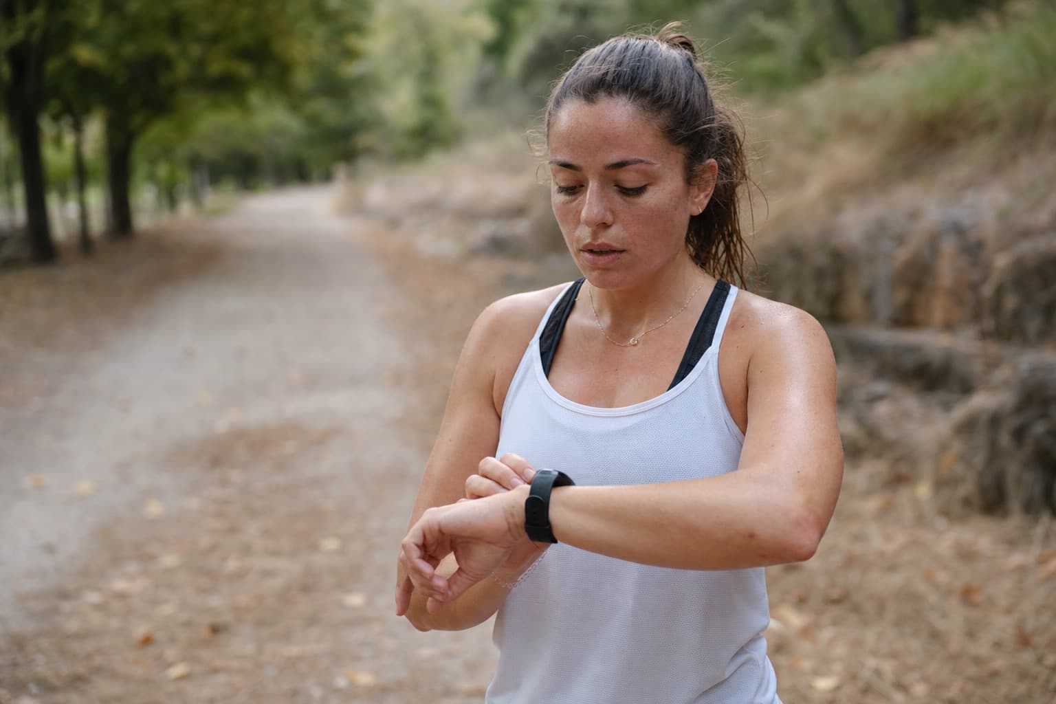Runner checking a wrist smartwatch during a cooldown after a run.