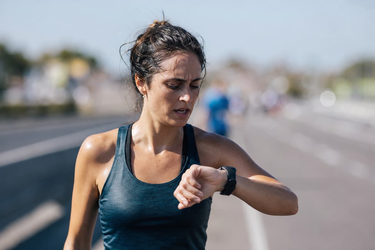 Marathon runner glancing at a wrist GPS watch during a hard qualifying effort.