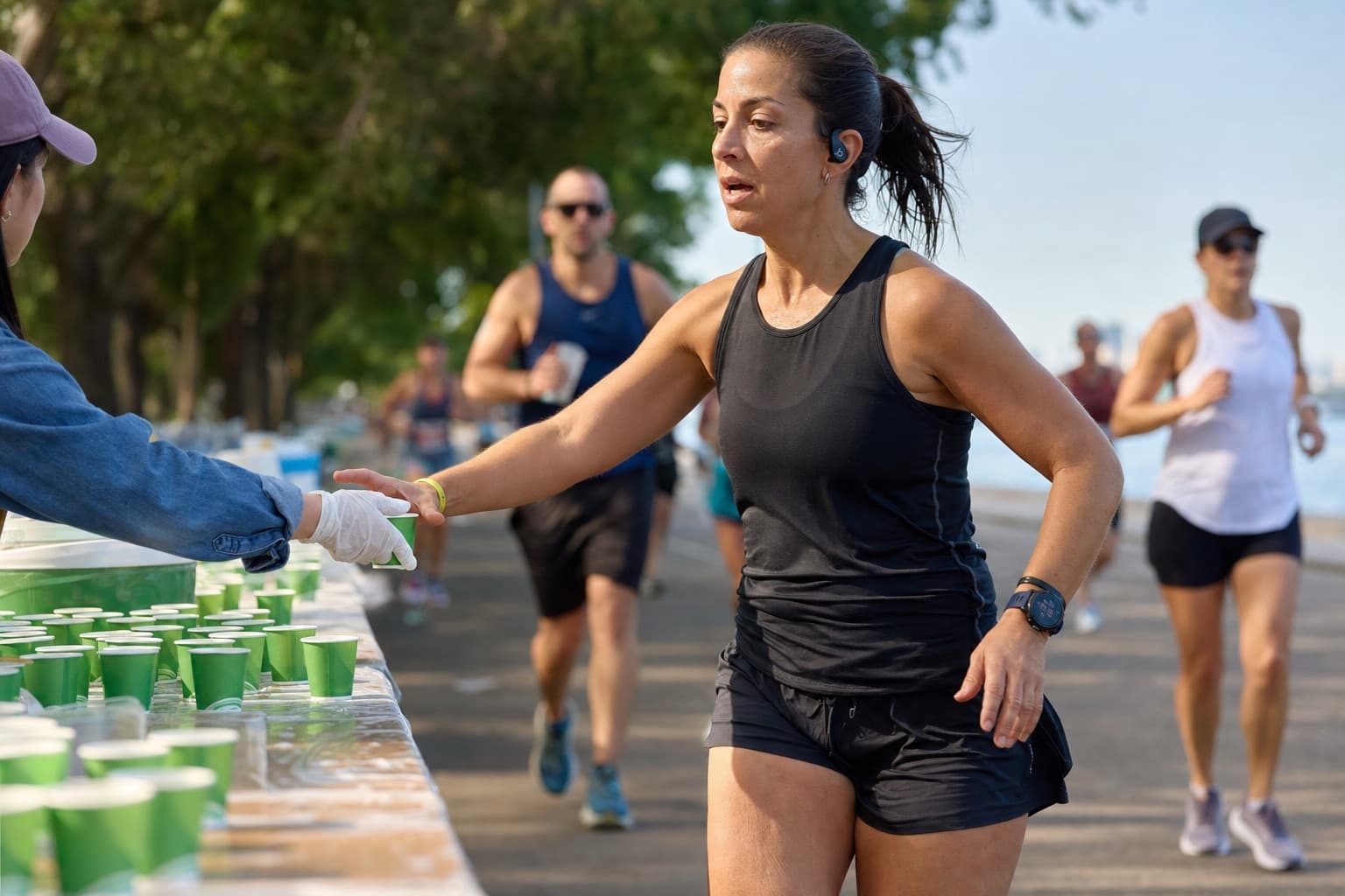Runner grabbing a cup of sports drink at a half marathon aid station.