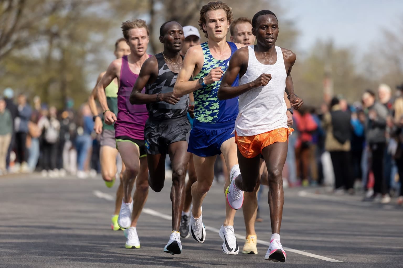 Small chase pack of 5K runners moving fast together early in a race.