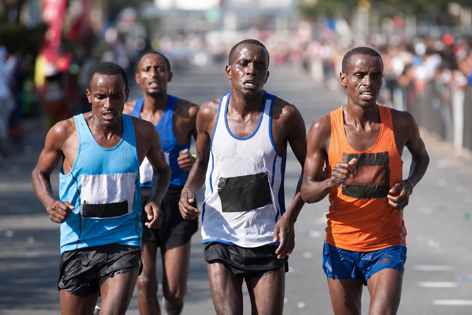 Small pack of marathon runners pushing through fatigue near the 30-kilometer mark.