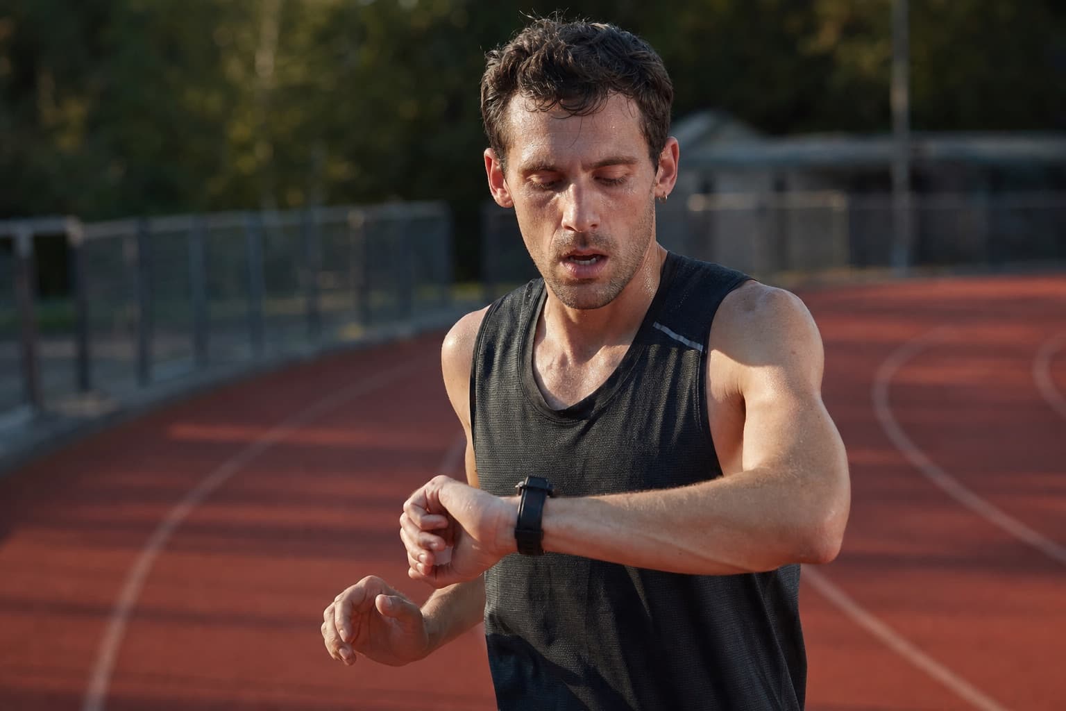 Runner glancing at a wrist watch during recovery from a fast track interval.