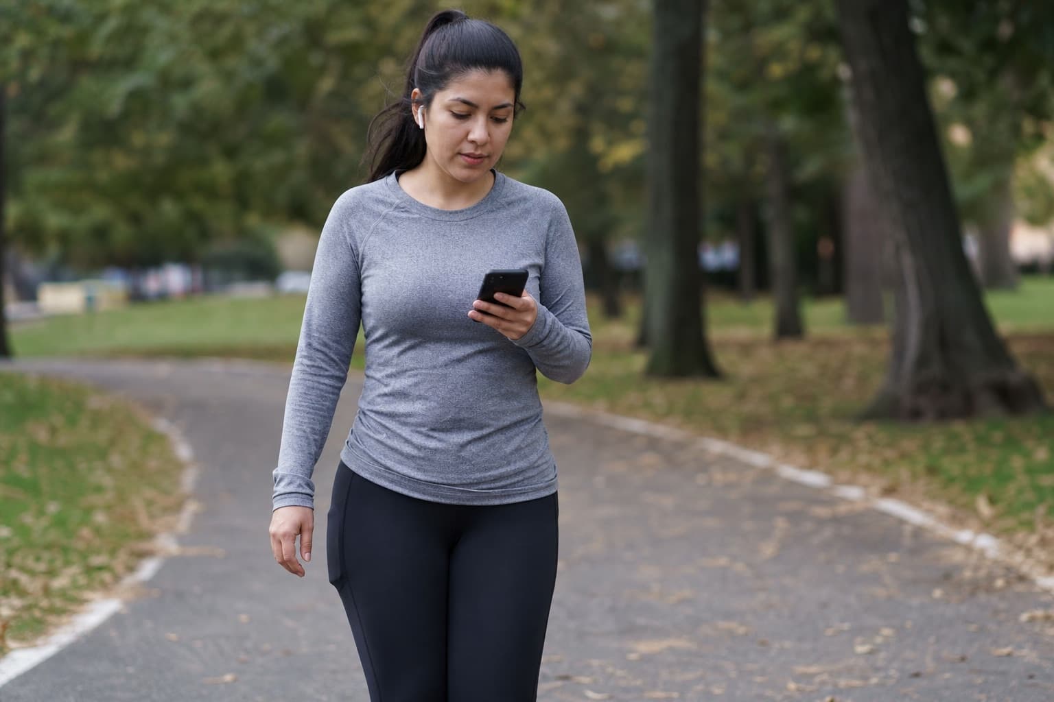 Beginner checking a phone timer during a walk-run training interval.
