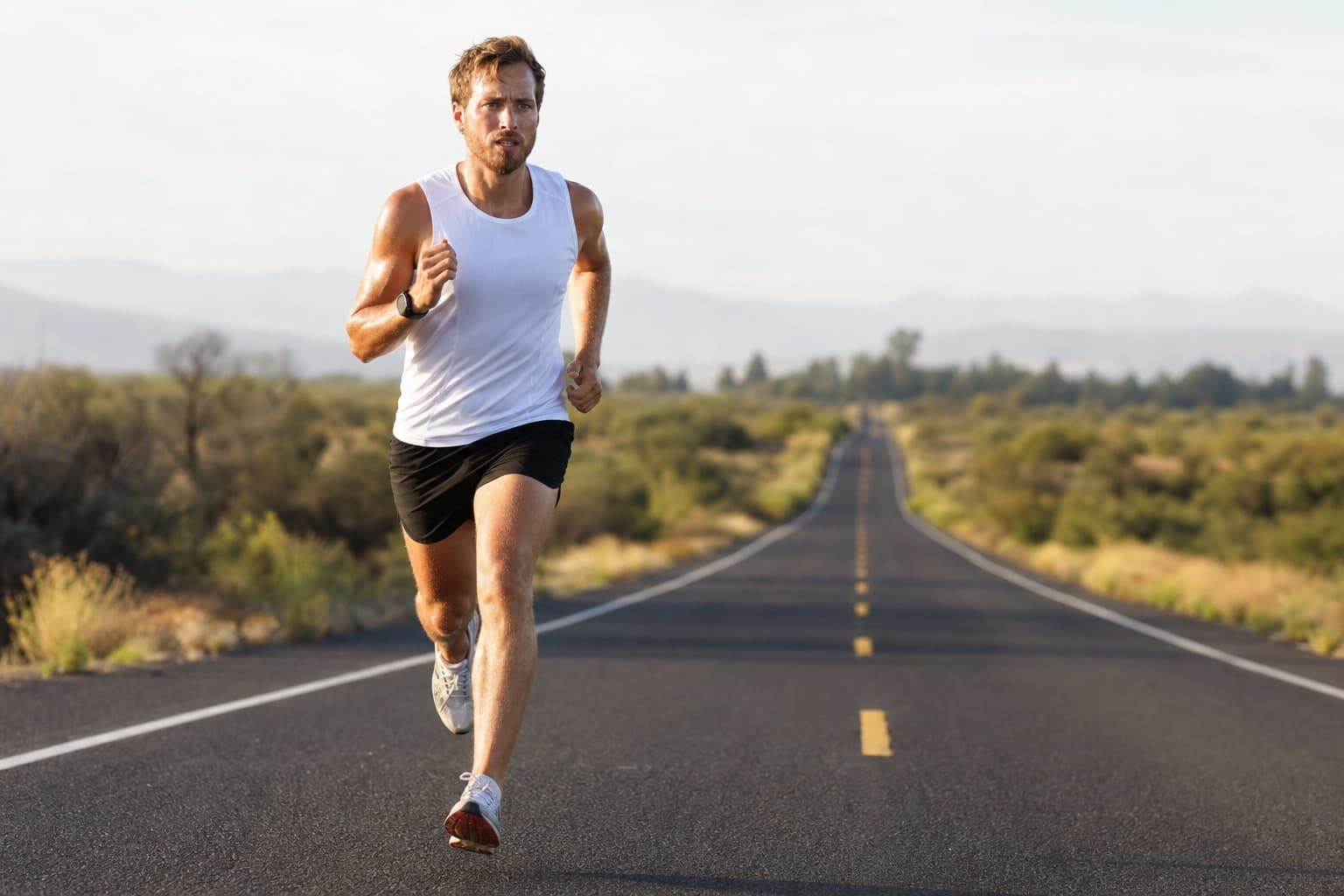 Runner in a focused, controlled quality effort on an open road.
