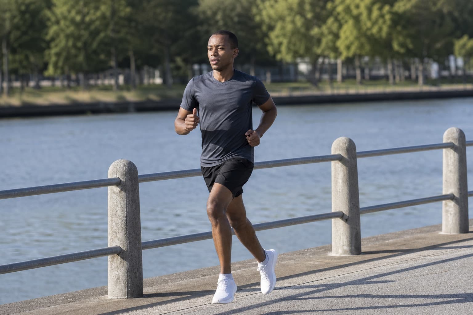 Runner in an honest, steady training effort along a riverside path.