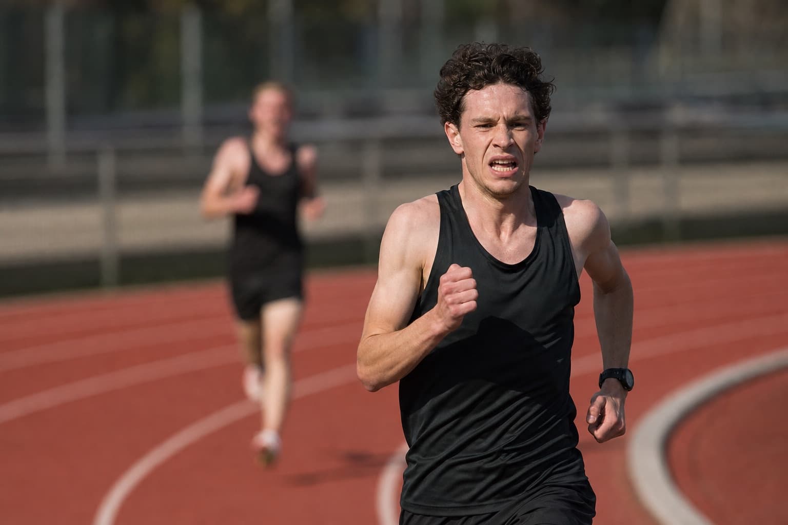 Runner pushing a hard threshold interval rep on an outdoor track.