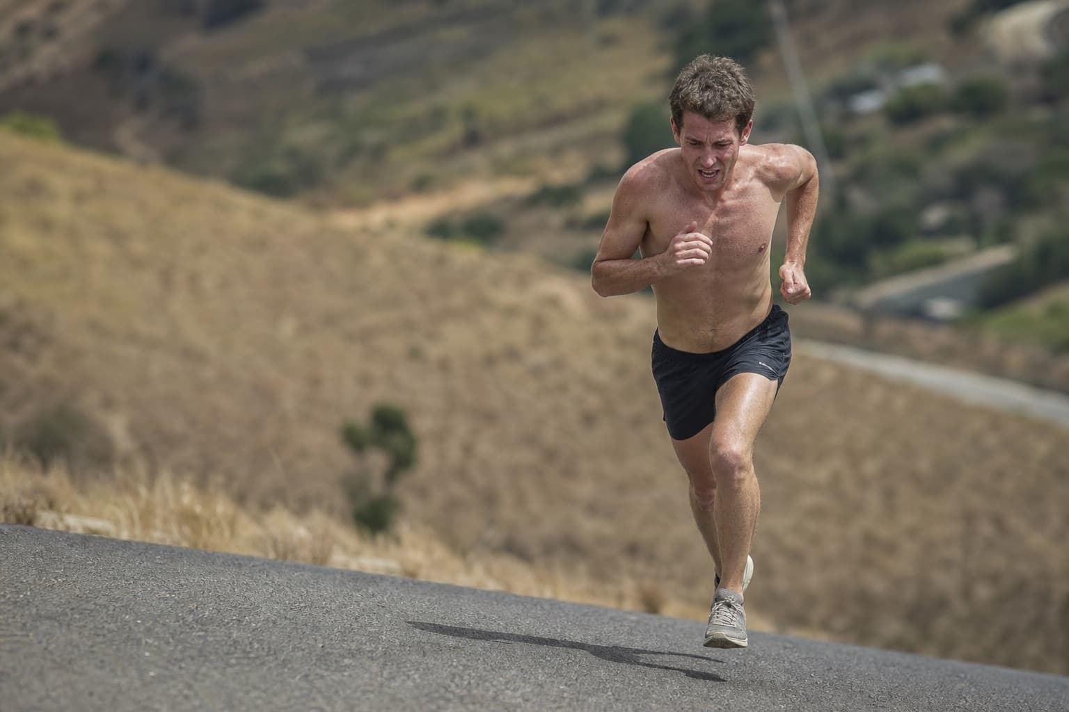 Runner sprinting hard up a steep hill during a training effort.