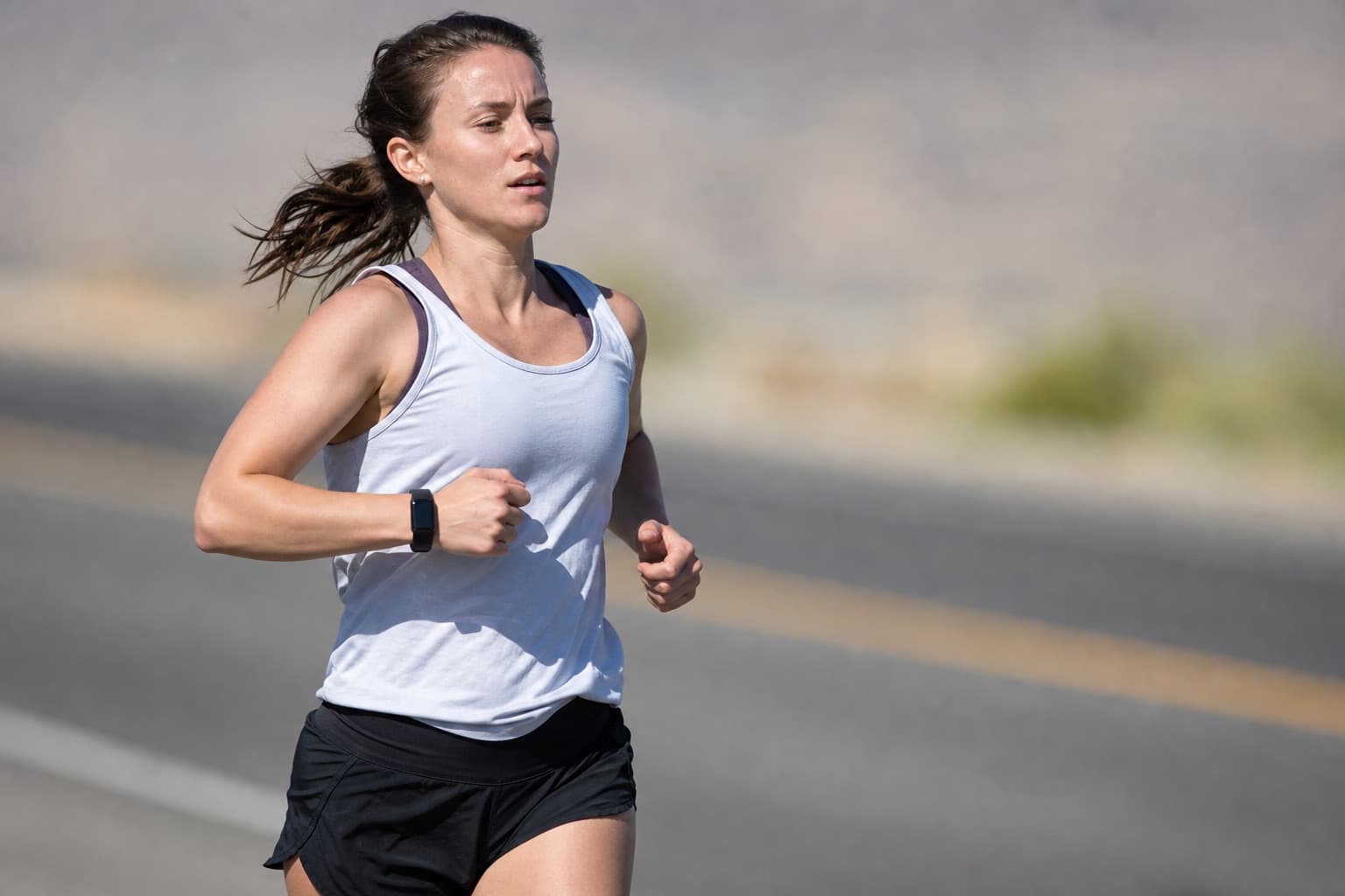 Runner taking quicker, shorter strides while running on an open road.