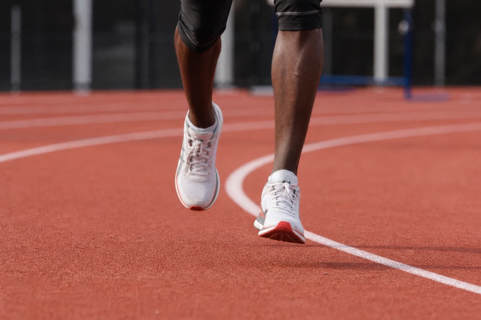 Close-up of a runner's feet mid-stride on a rubber track surface.