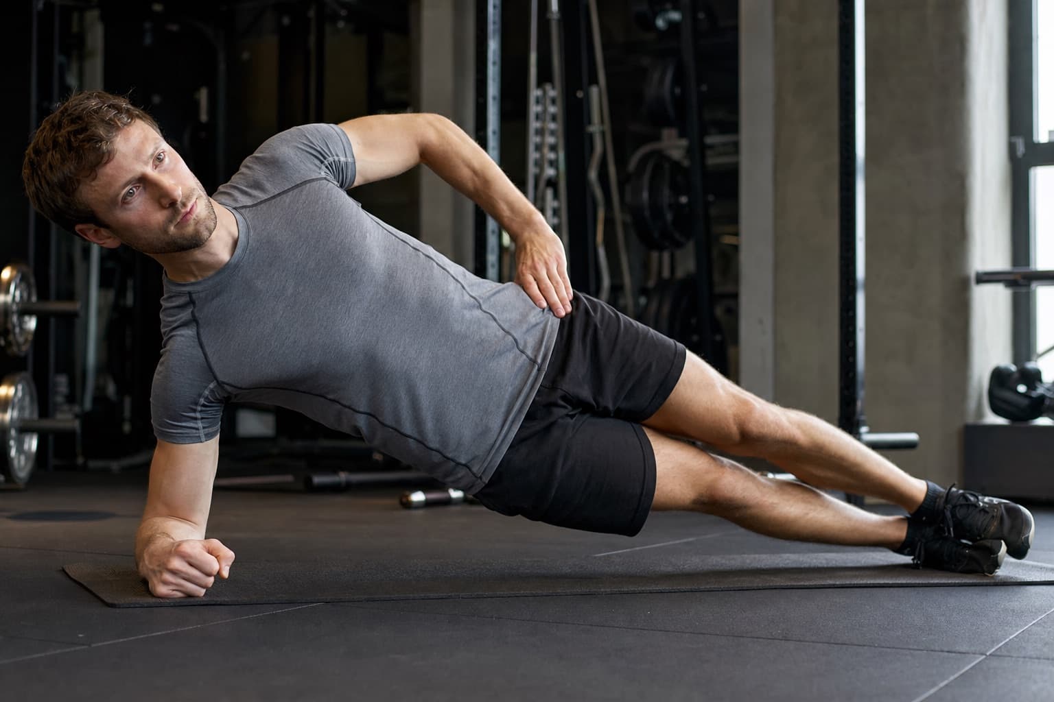 Runner holding a side plank exercise on a gym mat.