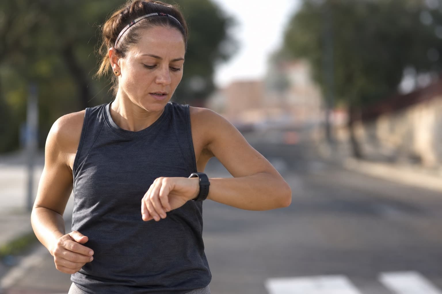 Runner glancing at a wrist watch to check their own pace.