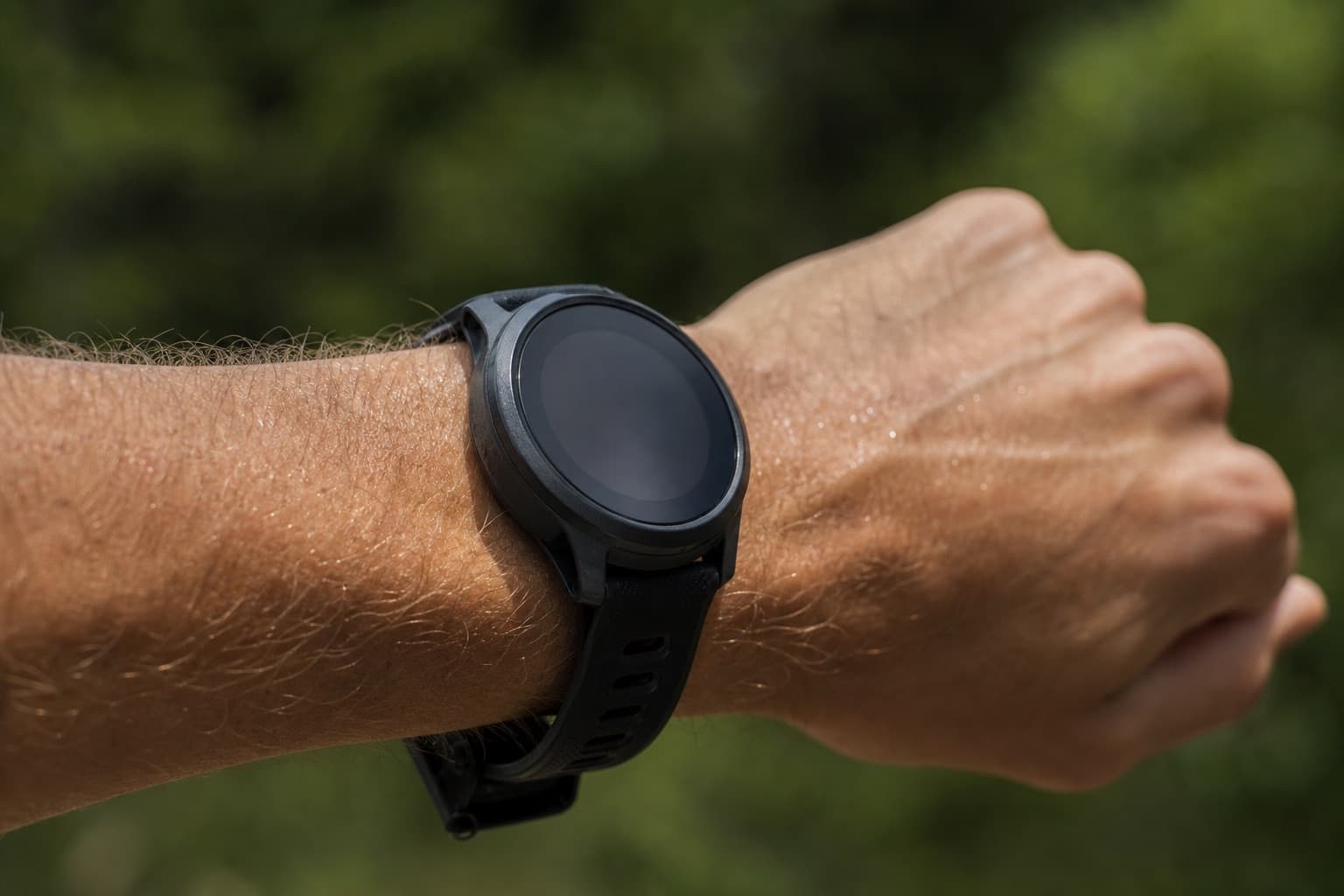 Macro view of a GPS sports watch on a runner's wrist outdoors.